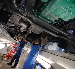 Underside view of a truck with 2 mechanics working on it